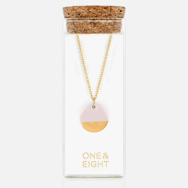 Necklace with a gold and white pendant in a 'One & Eight' packaging on a white background