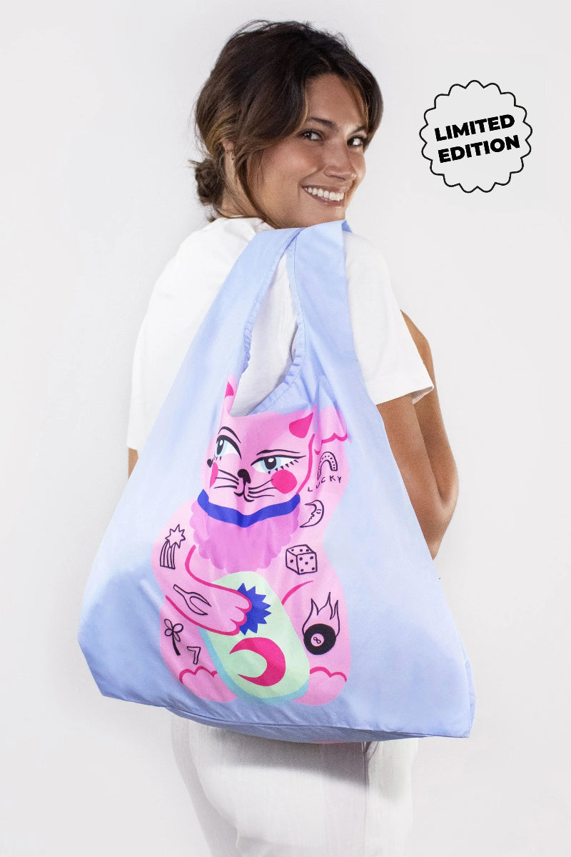 Person holding a blue drawstring bag with a colorful cat design, labeled 'Limited Edition'.