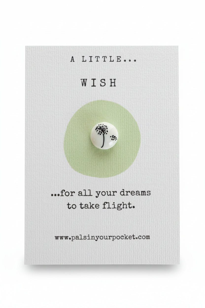 A square white card with textured paper lies on a brown wooden surface. The card reads 'A LITTLE.