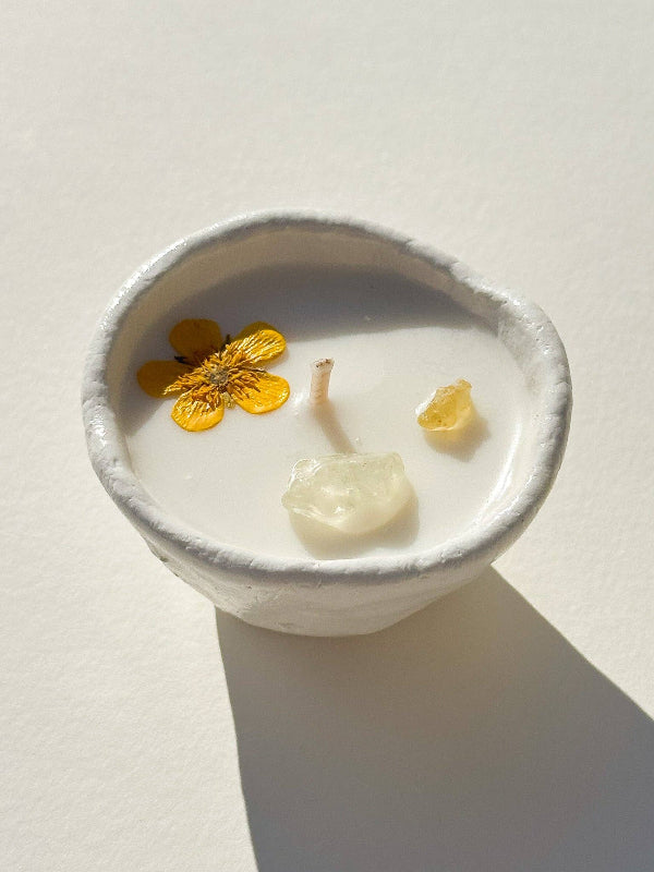 Candle in a white container with floral elements on a light background