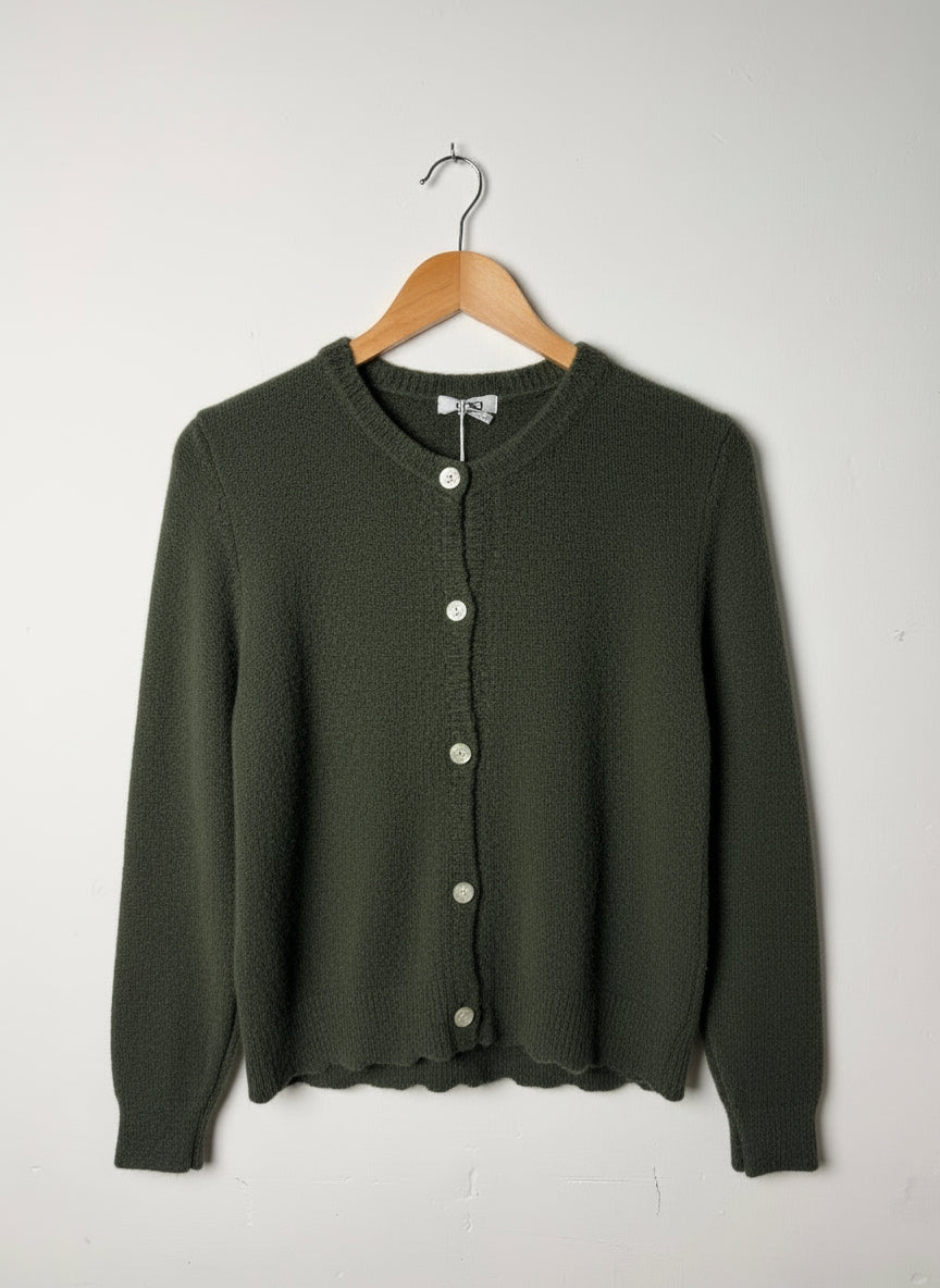 Green cardigan on a wooden hanger against a white background