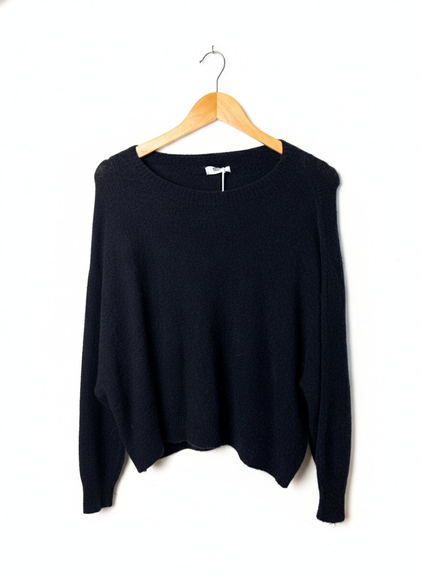 Black sweater on a wooden hanger against a white background