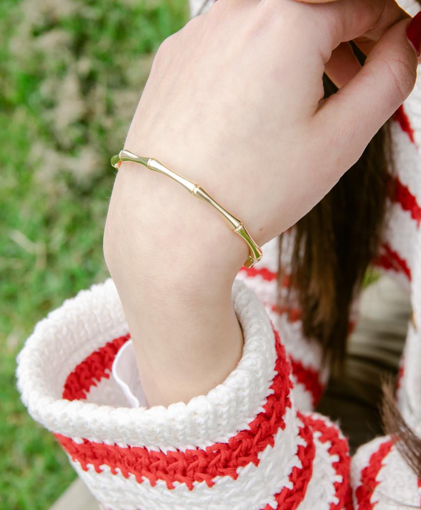 Gold bracelet on a wrist with a blurred green background