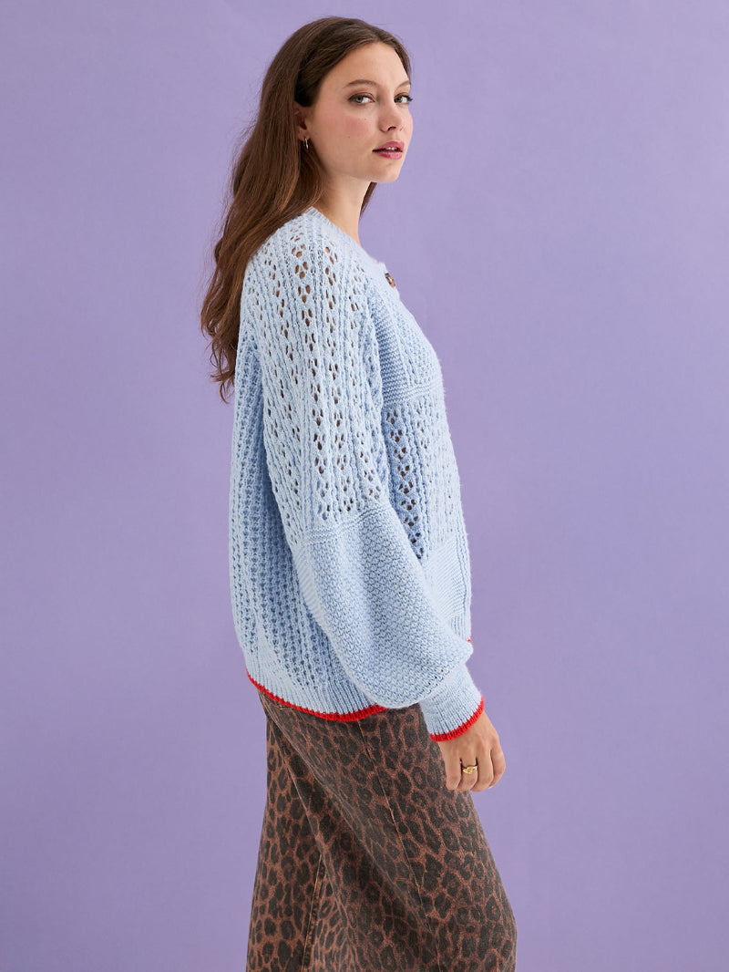 Woman wearing a light blue knitted sweater against a purple background