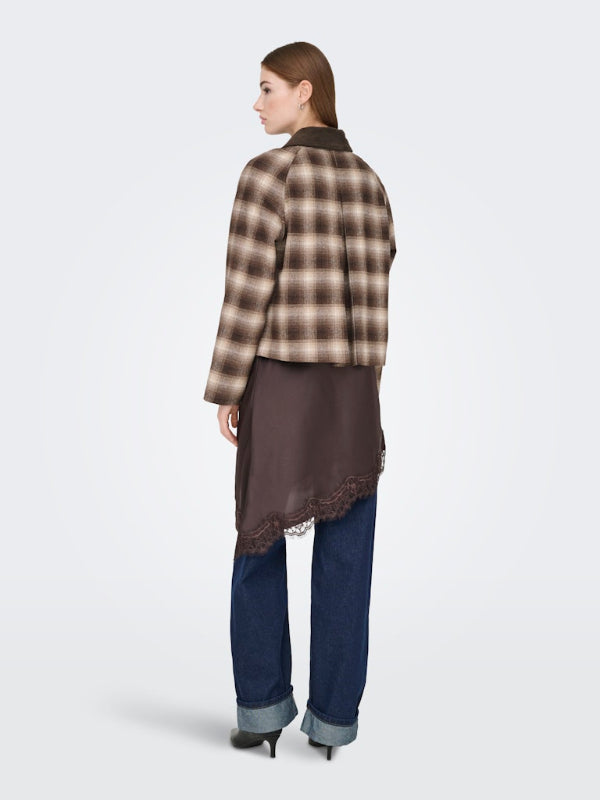 Woman wearing a plaid shirt over a brown top with blue pants on a white background