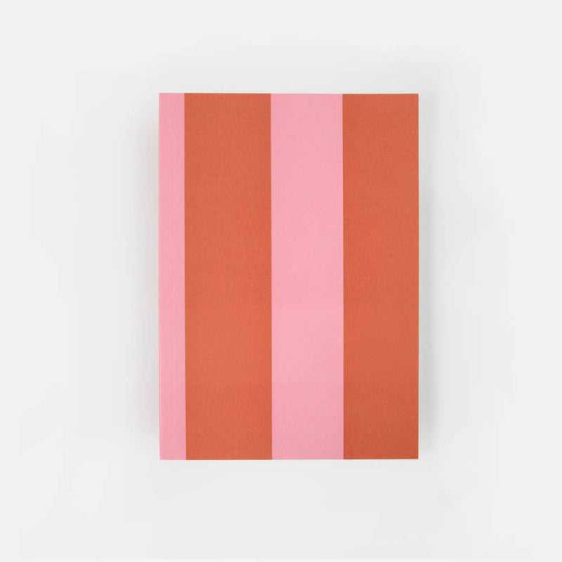 A rectangular notebook or journal with vertical stripes in pink, terracotta orange, and a lighter pink, displayed on a clean white background.