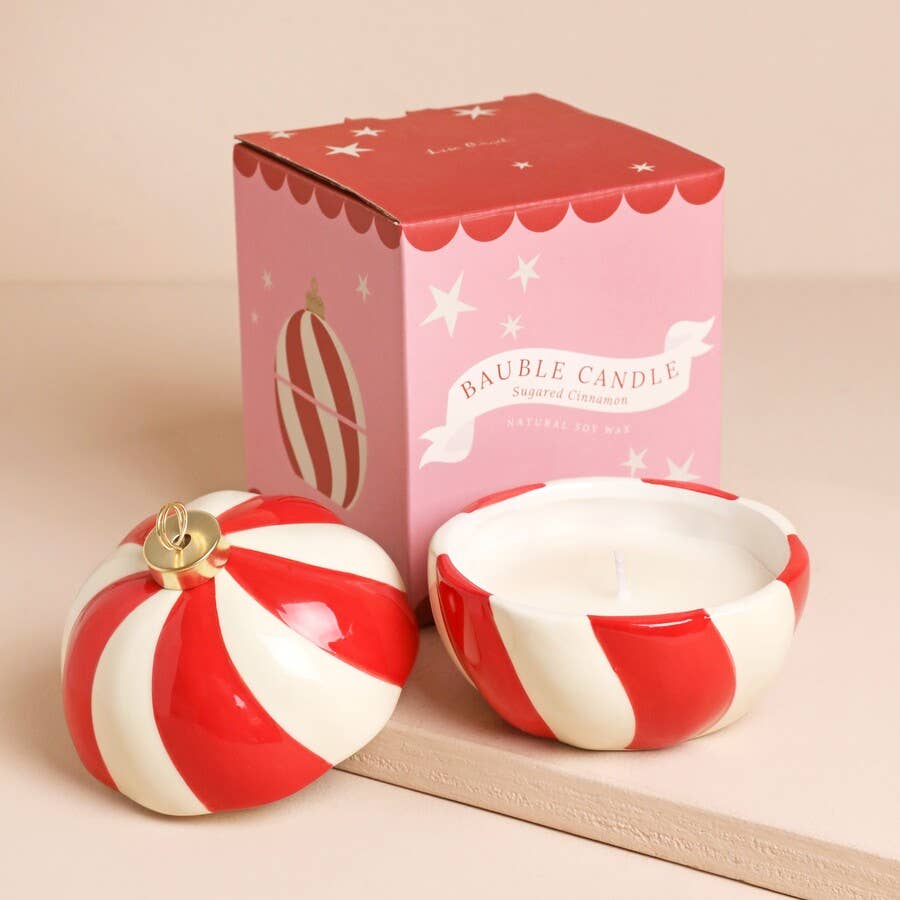 Red and white striped candy cane-shaped candle with matching box on a beige background