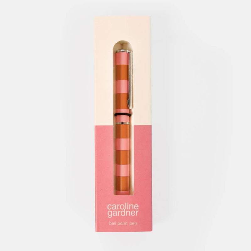 A Caroline Gardner ball point pen with a pink and orange striped pattern and gold accents, presented inside its cream and pink packaging box against a white background.