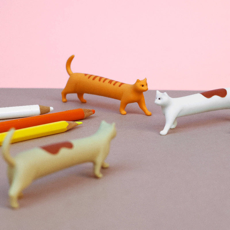 Cat-shaped pencil holders on a pink background