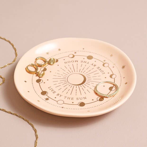 Jewelry dish with celestial design and jewelry on a beige background