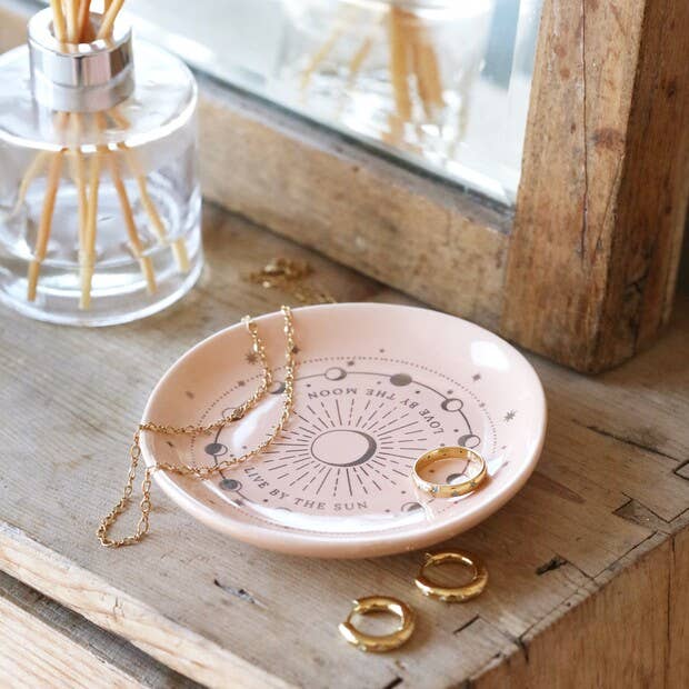 Jewelry dish with necklaces and rings on a wooden surface