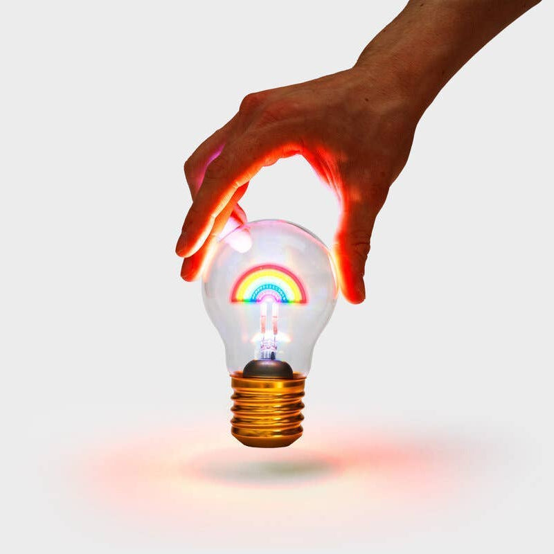 Hand holding a light bulb with a rainbow inside, on a white background