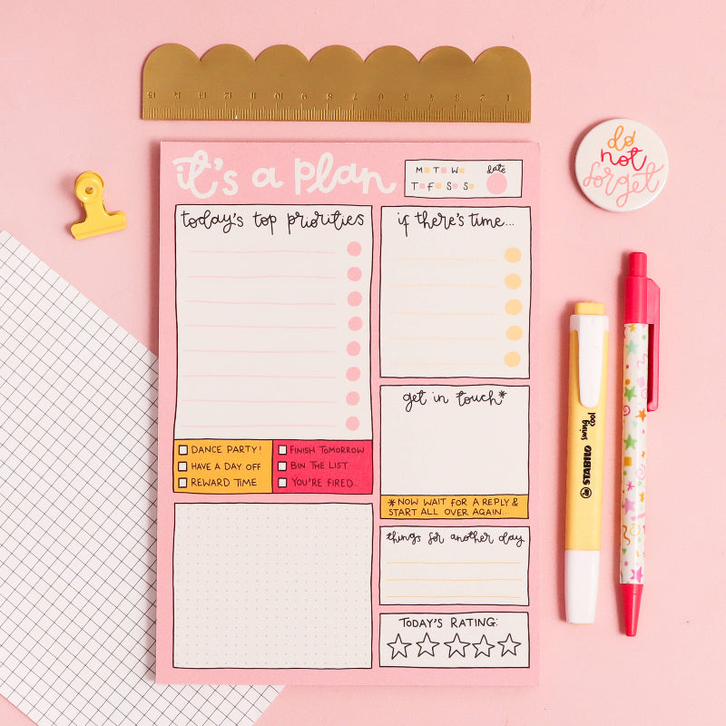 Notebook with planner stickers, markers, and a ruler on a pink background