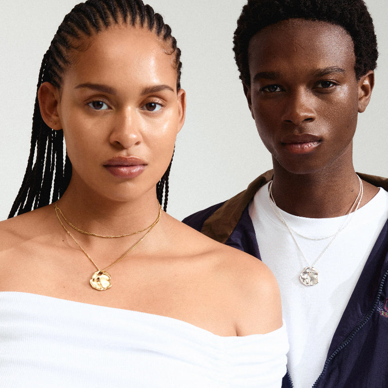 Two people wearing necklaces against a neutral background