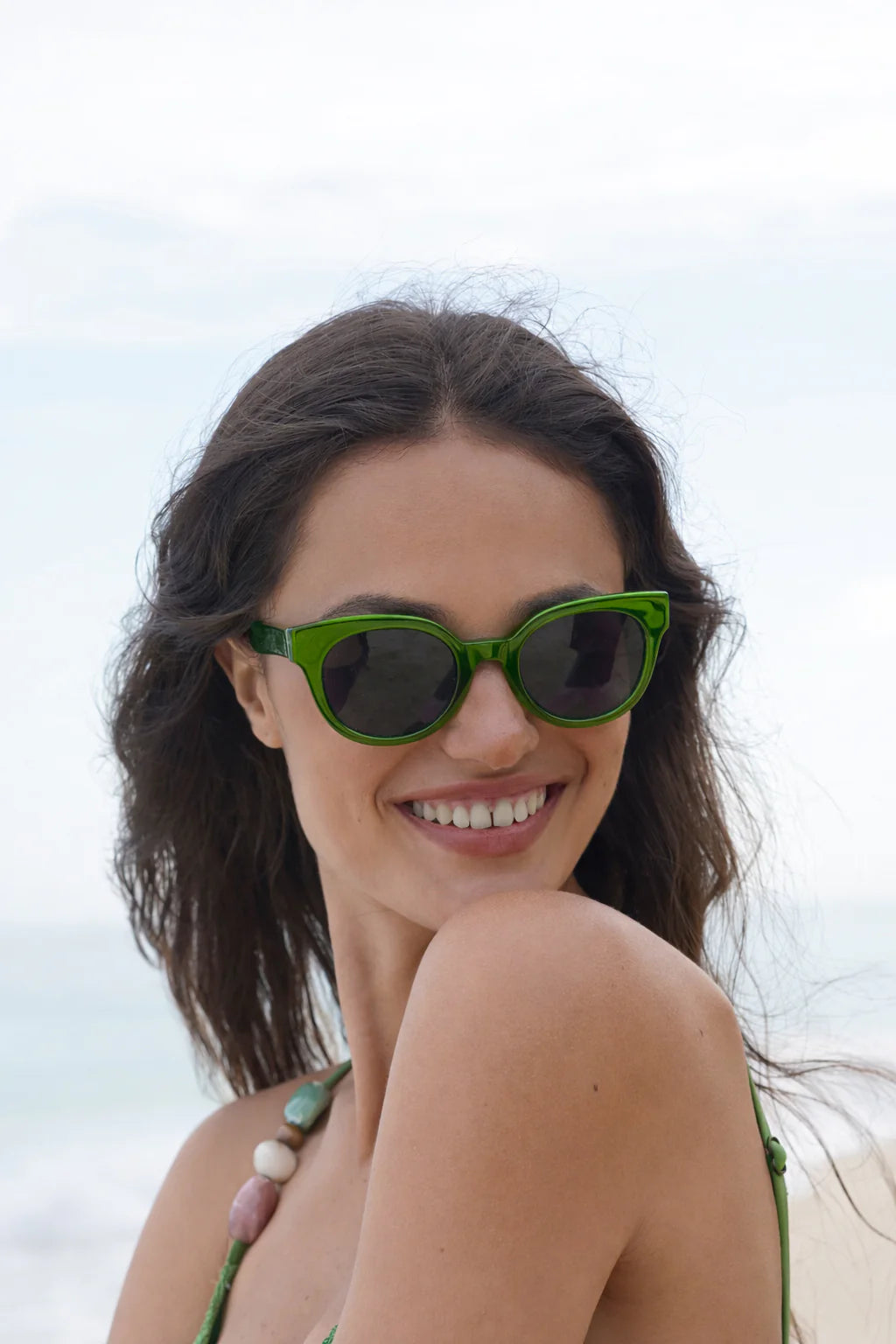 Woman wearing Estella bartlett Seaol green sunglasses with a blurred background