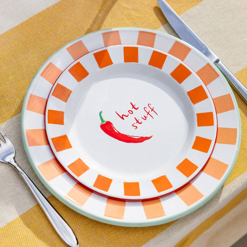 Decorative plate with orange and white pattern and 'hot stuff' text on a yellow tablecloth.