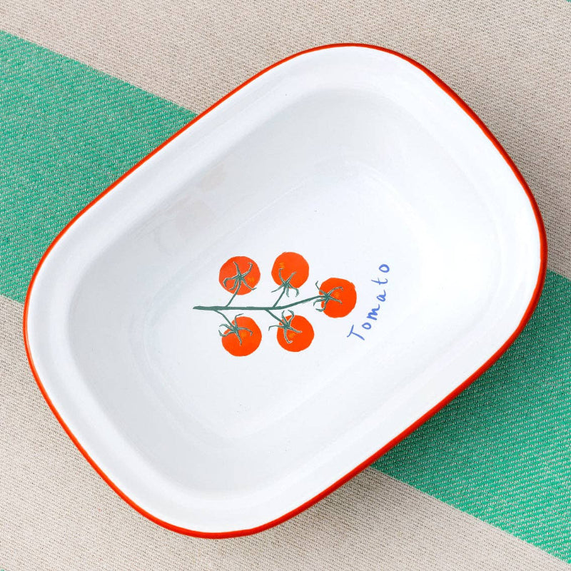 White dish with red rim featuring a tomato design on a green and beige striped background