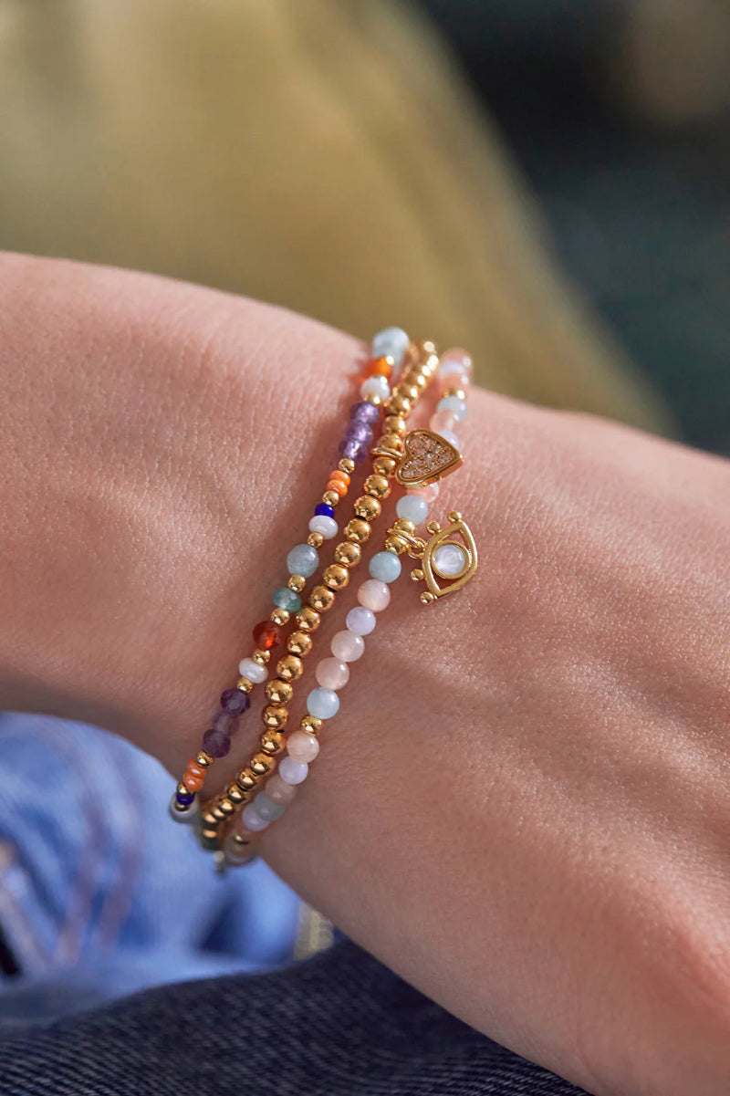 Close-up of a wrist wearing multiple beaded bracelets with a blurred background