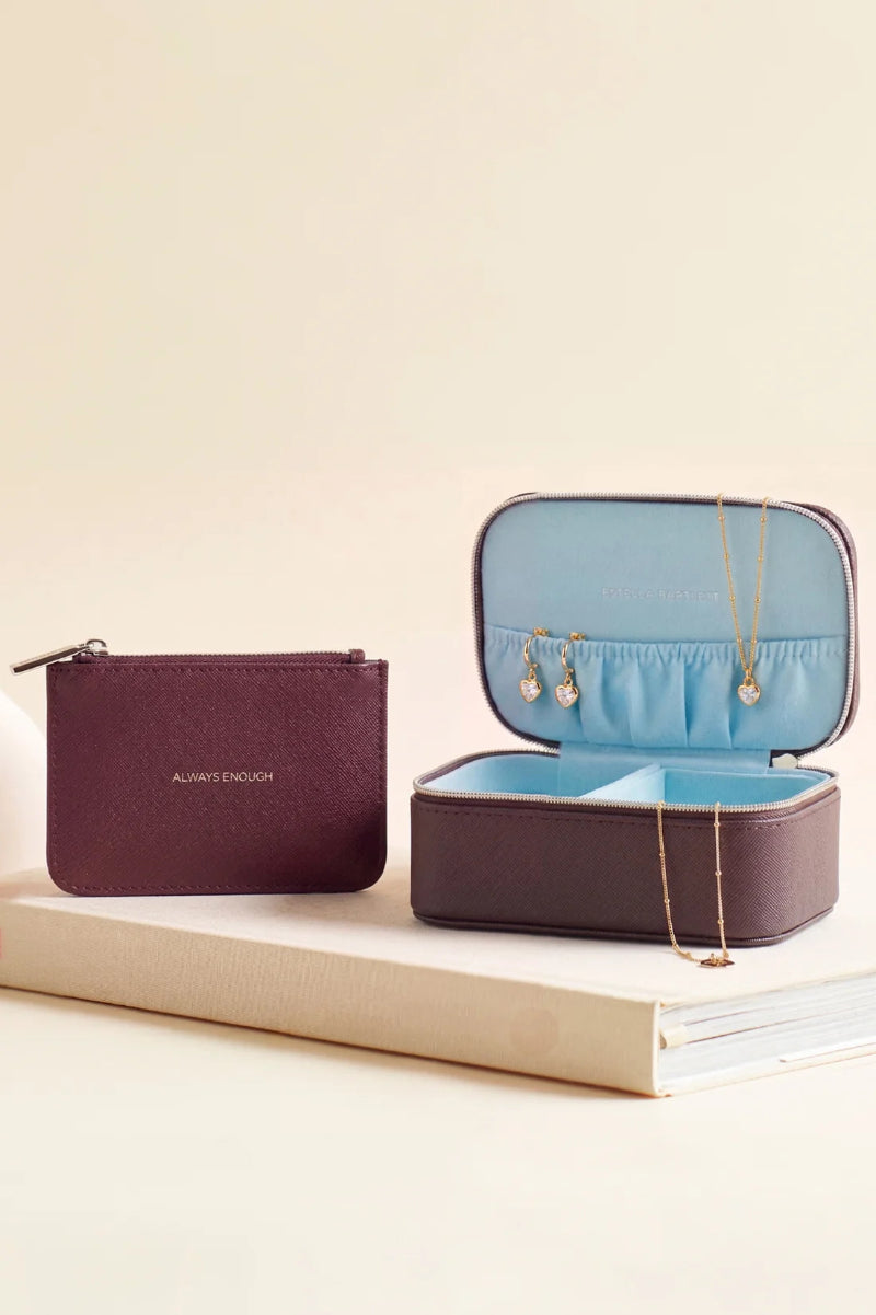 Jewelry case with open lid displaying jewelry, closed purple case on a beige surface