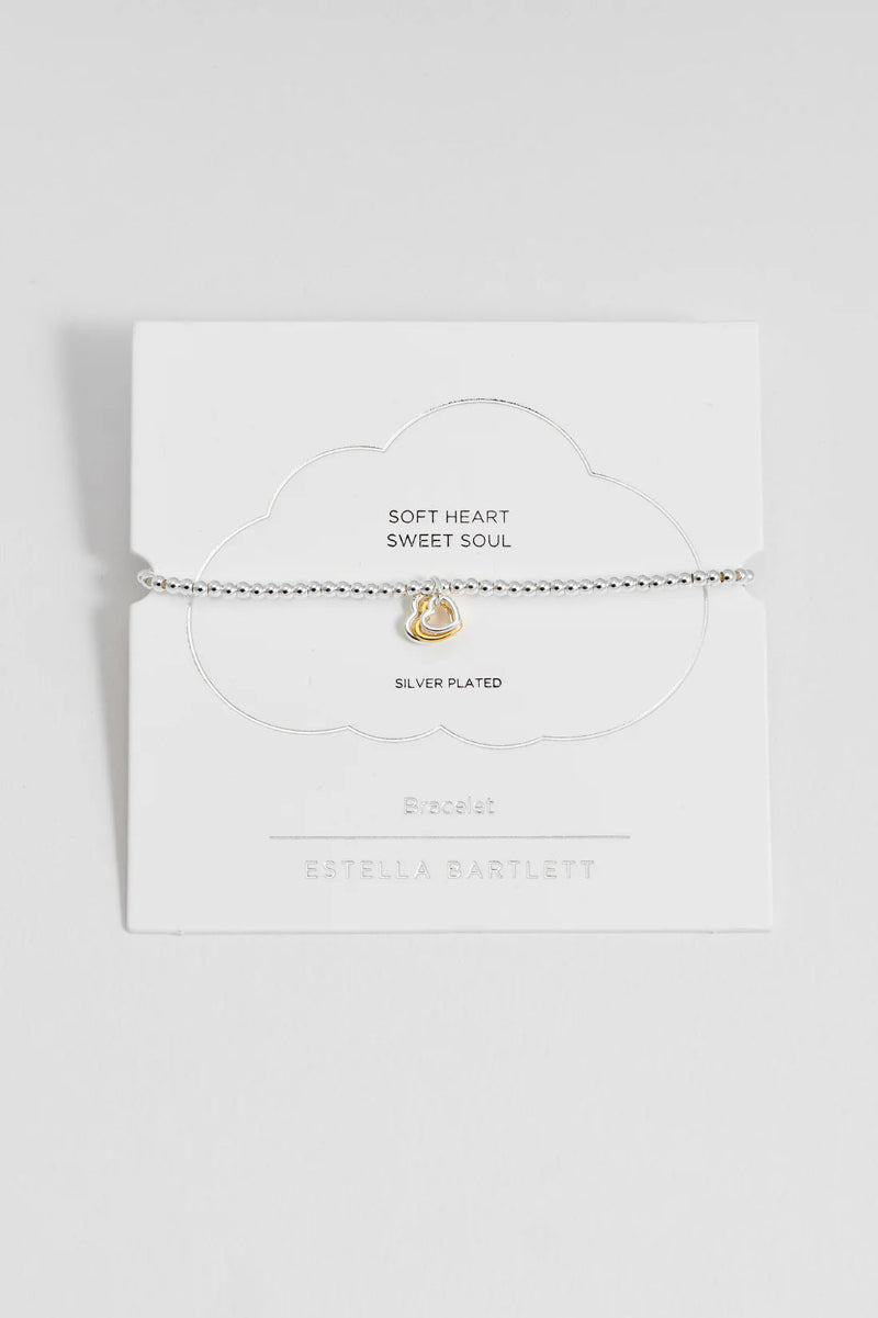 White pouch with gold heart charm and text on a light gray background