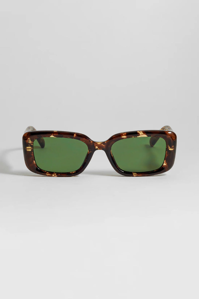 Sunglasses with tortoiseshell frame and green lenses on a light gray background