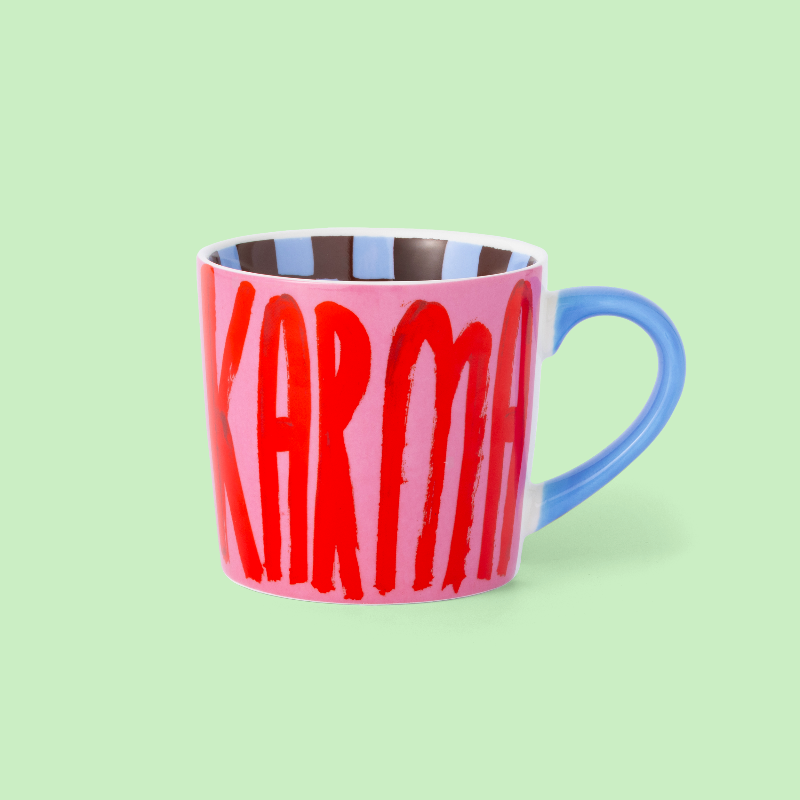 Pink mug with blue handle and red text on a light green background