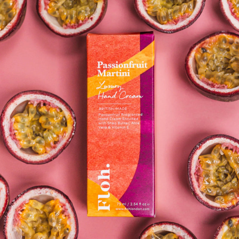 Passionfruit Martini hand cream box surrounded by passionfruit halves on a pink background