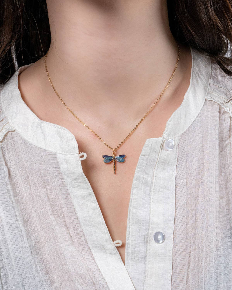 Necklace with a Fable England blue butterfly pendant worn by a person in a white shirt.