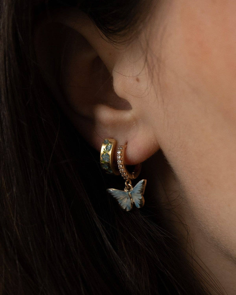 Close-up of an ear wearing a Fable Enamel Blue Butterfly Huggie Earrings