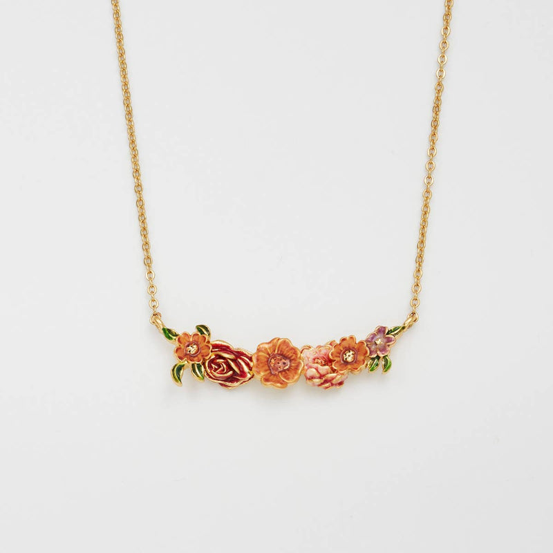 A gold chain necklace featuring a horizontal bar with three small 3D roses in orange, pink, and red tones, accented with green leaves and clear rhinestones, on a plain white background.