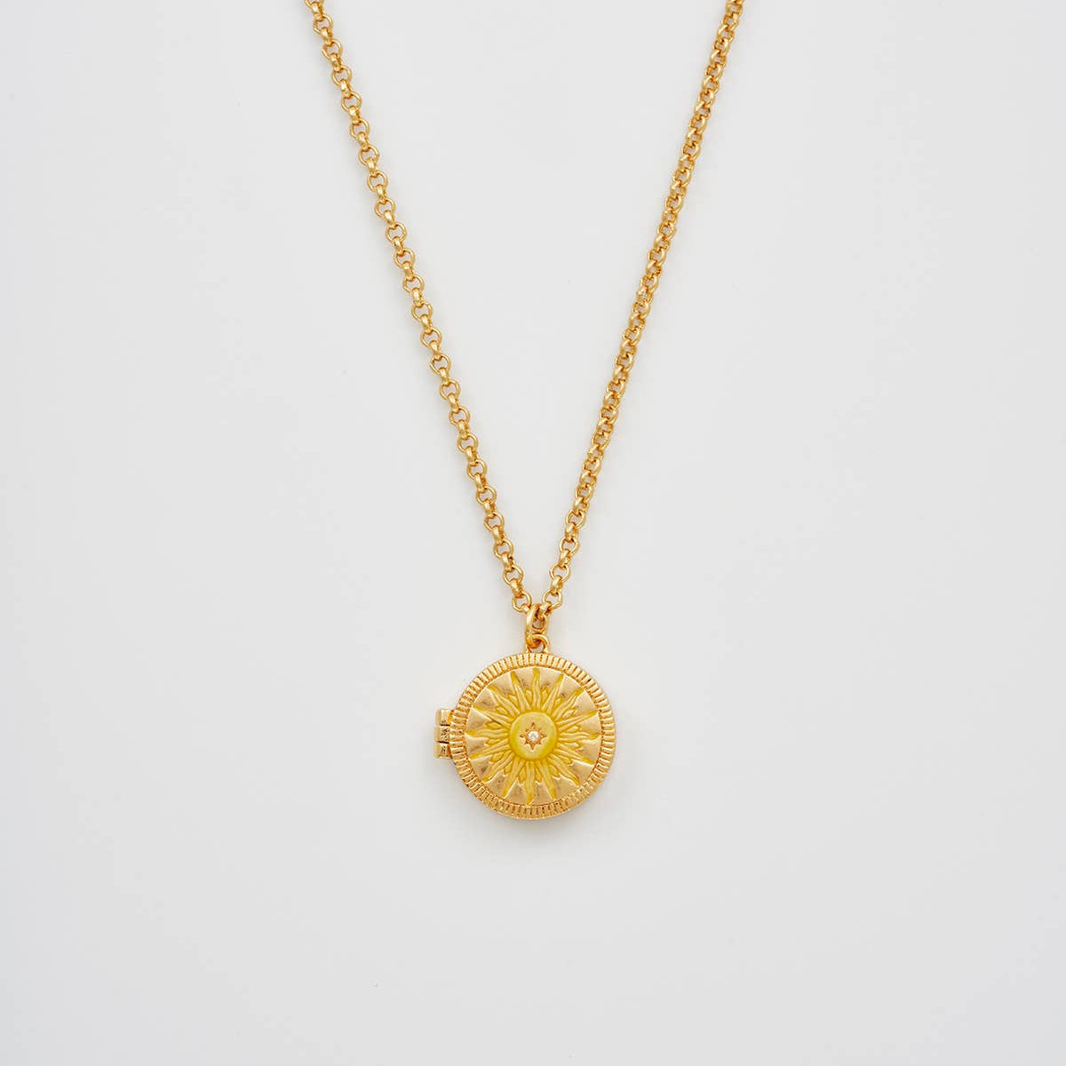 Gold necklace with a sun-shaped pendant on a light gray background