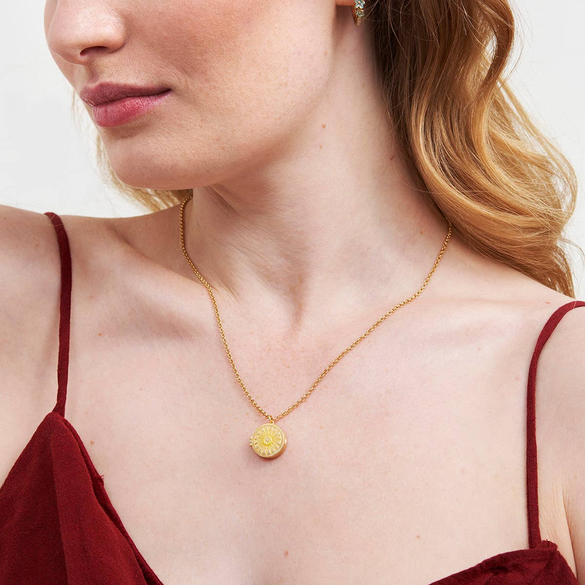 Woman wearing a gold necklace and earrings on a plain background