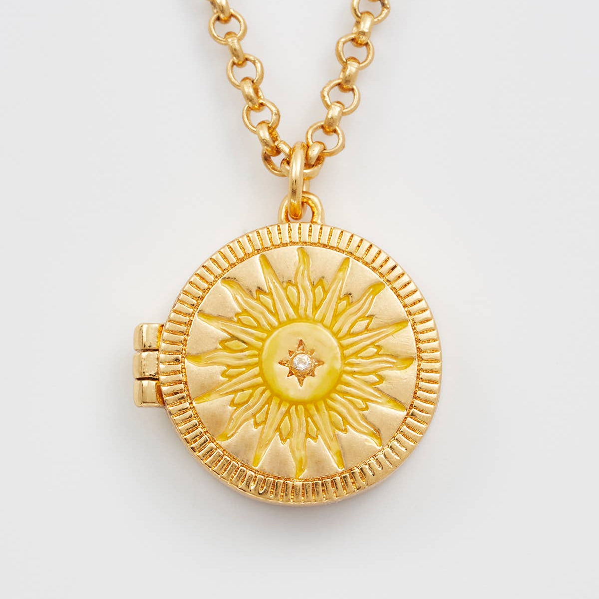 Gold necklace with a sun-shaped pendant on a light gray background