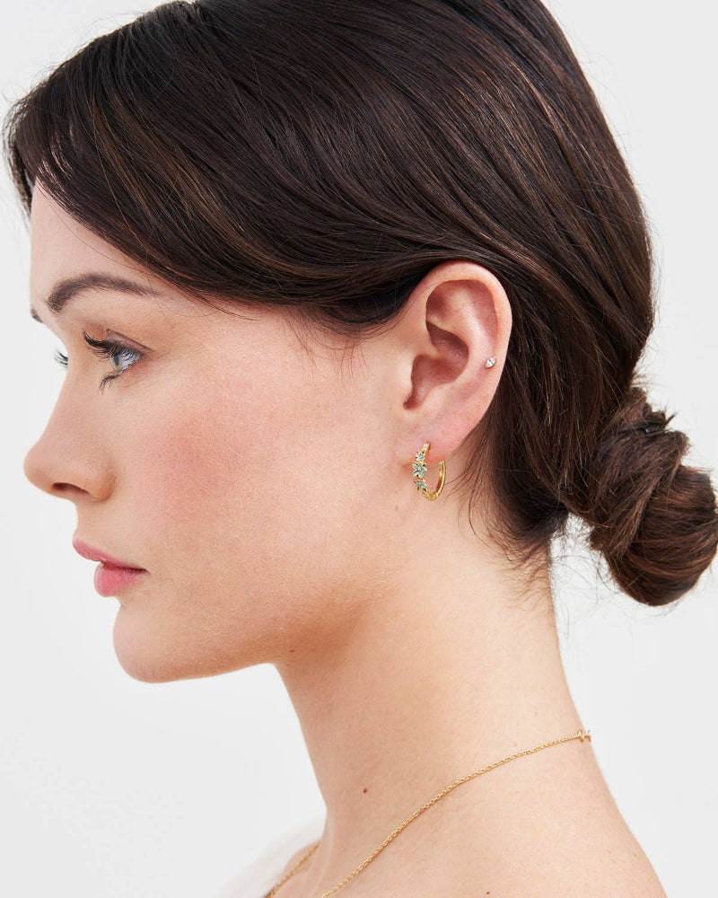 Woman wearing Fable Englandgold hoop earrings with a plain background