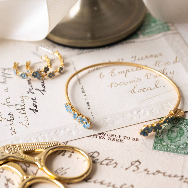 GoFable Forget-Me-Not Bangle and earrings on vintage letters with a stamp.