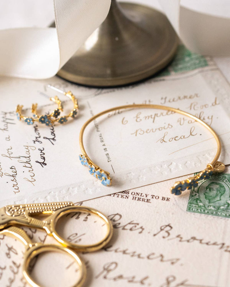 GoFable Forget-Me-Not Bangle and earrings on vintage letters with a stamp.