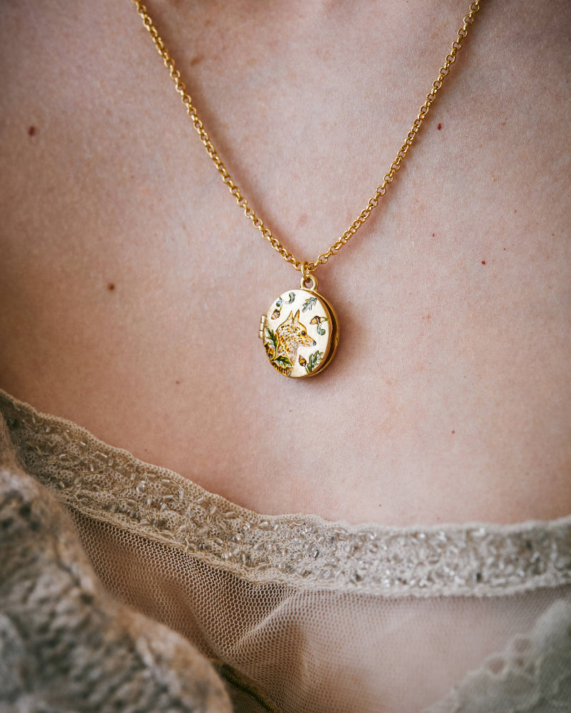 Gold necklace with a pendant on a person wearing a sheer lace garment.