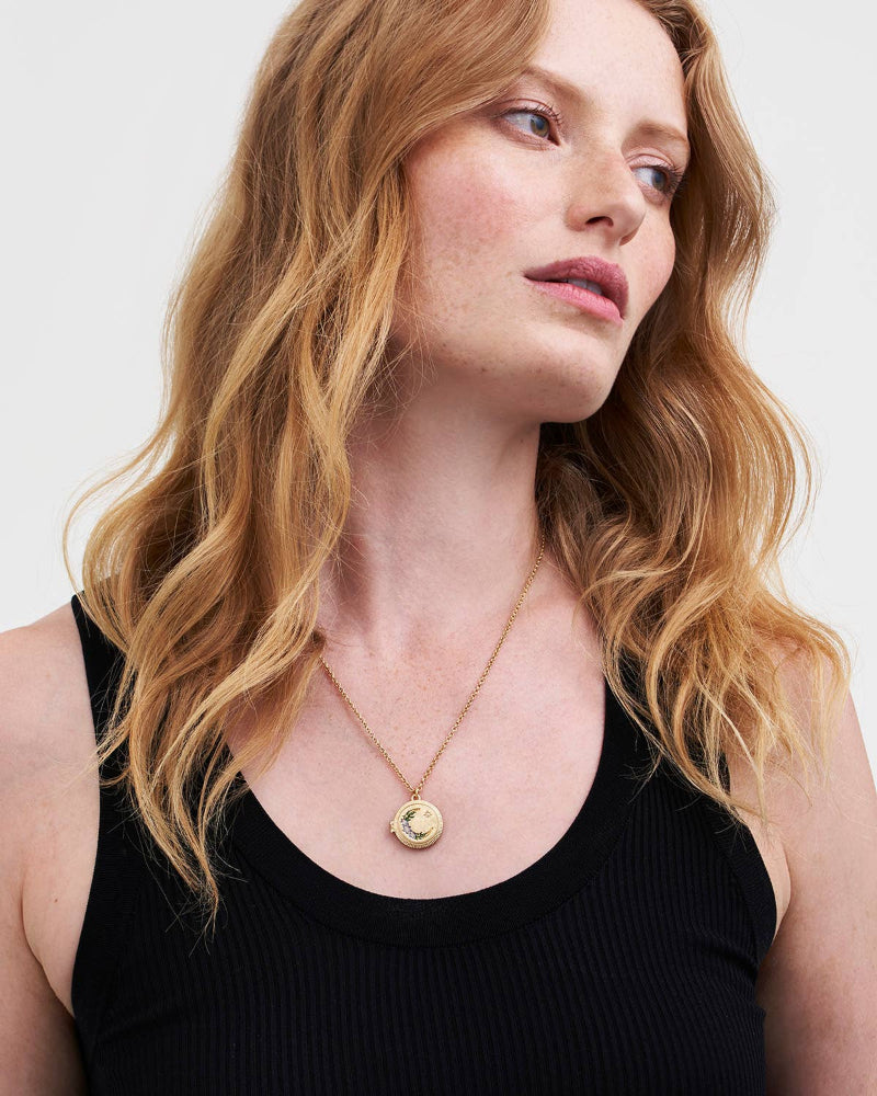 Woman wearing a Fable Nightshade Moon Round Gold Locket Chain Necklace with a pendant against a plain background