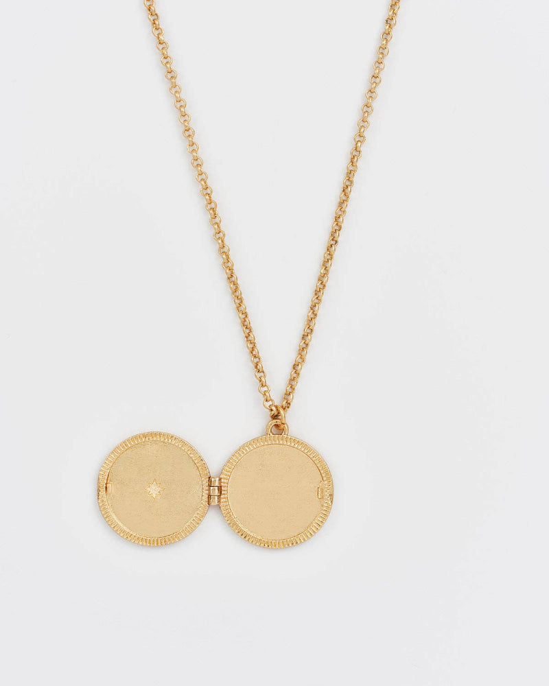 Gold necklace with a round pendant on a white background
