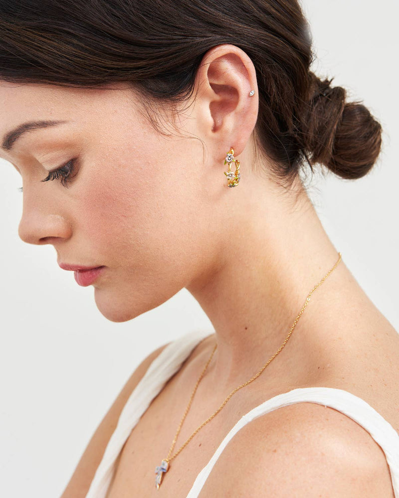 Close-up of a woman wearing gFable Wildflower Garden Hoop Earrings and a necklace with a white background