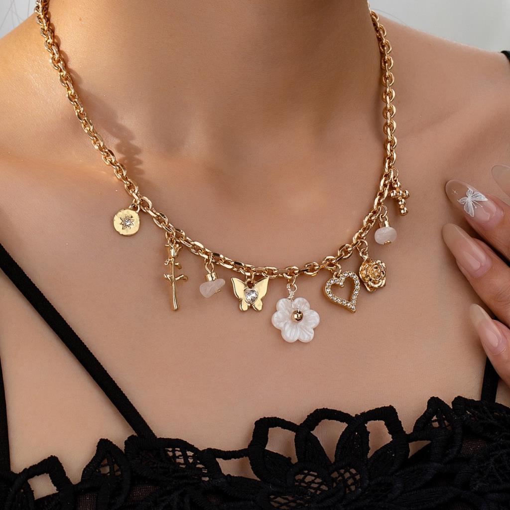 Gold necklace with various charms on a person wearing a black top.