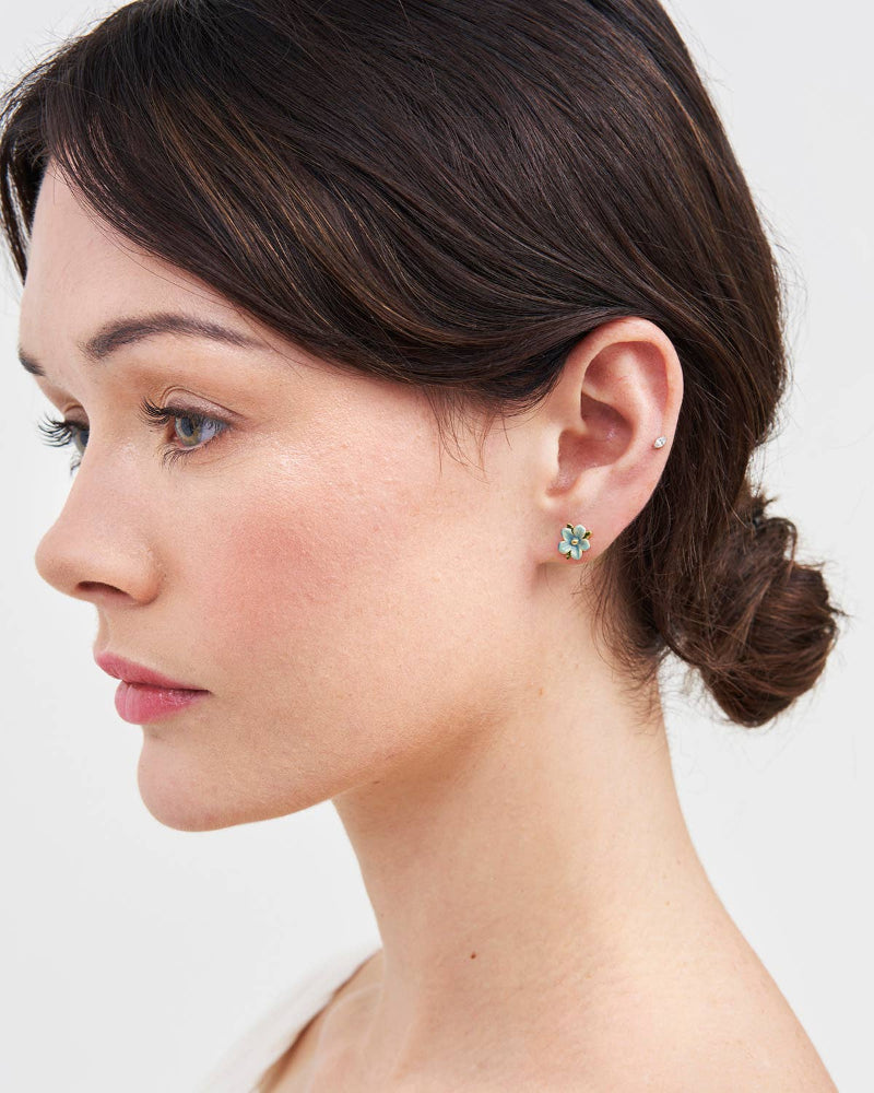 Woman wearing a green earring on a plain background