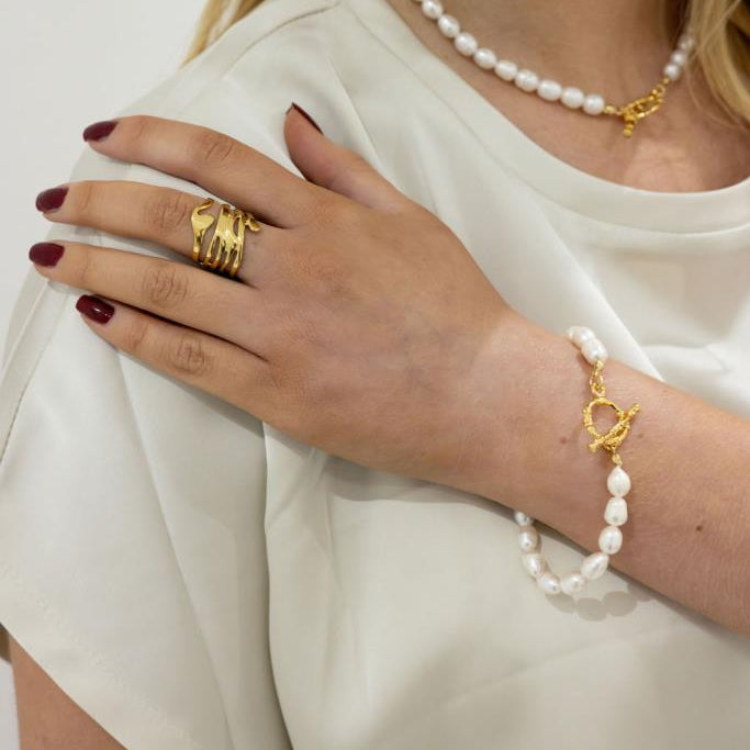 Close-up of a person wearing gold jewelry with a plain background