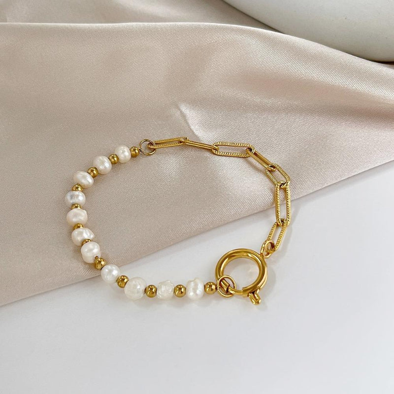 Gold bracelet with pearl beads on a beige fabric background