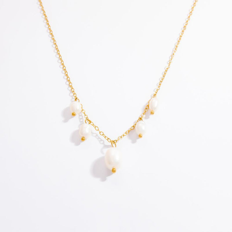 Gold necklace with small white stones on a light gray background