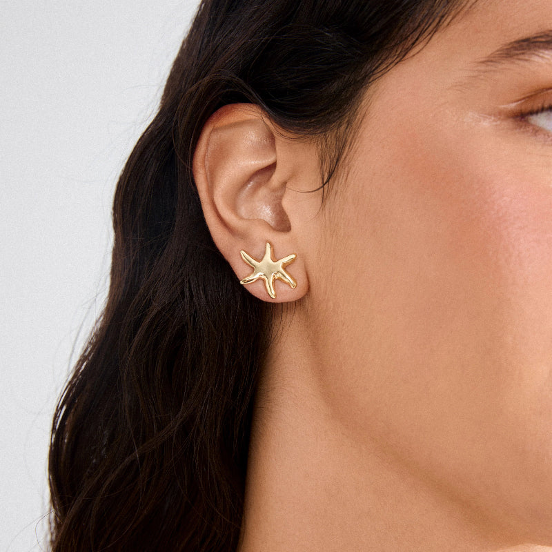A woman wearing gold earrings against a white background