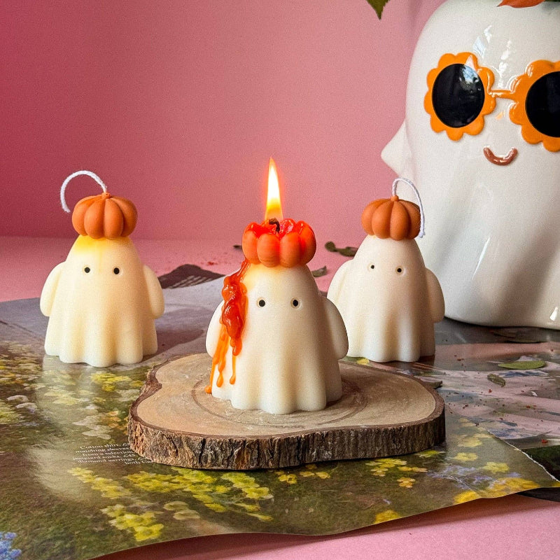 Halloween-themed candles with ghost and pumpkin designs on a wooden base.