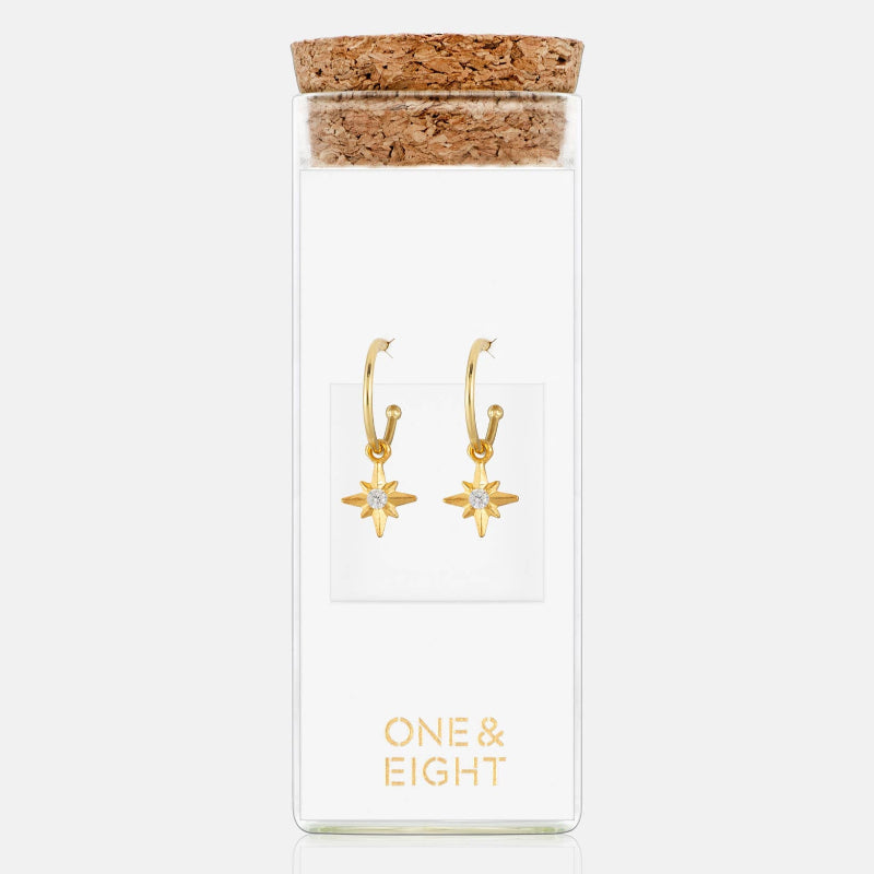 Gold star-shaped earrings in a 'ONE & EIGHT' branded box on a white background