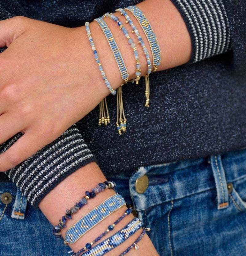 Person wearing multiple beaded bracelets on a white background