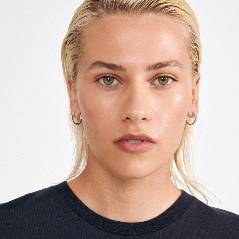 Person with blonde hair wearing a black top on a white background